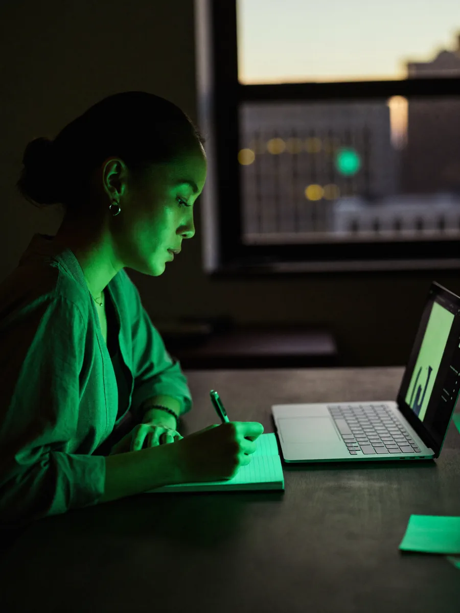 A woman writing at her desk before sunrise