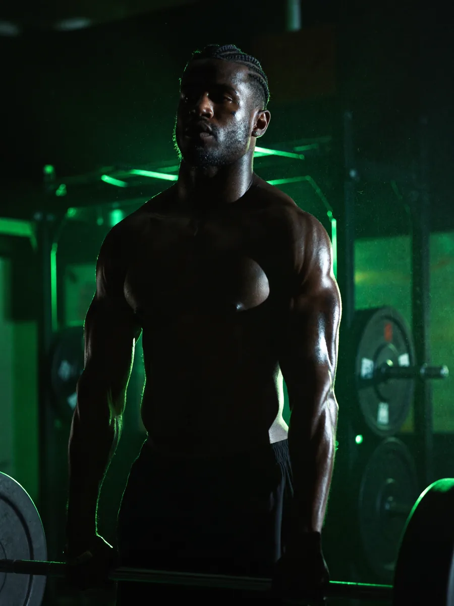 An athlete gripping a loaded barbell in a dark gym